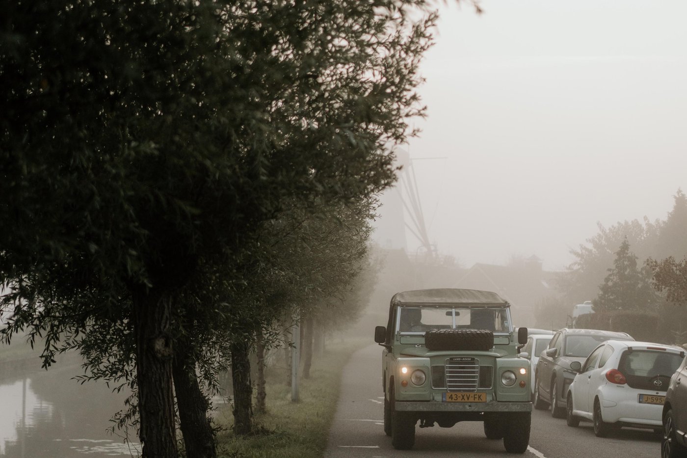 Land Rover Series 88 rijdt over een mistige weg langs de bomen
