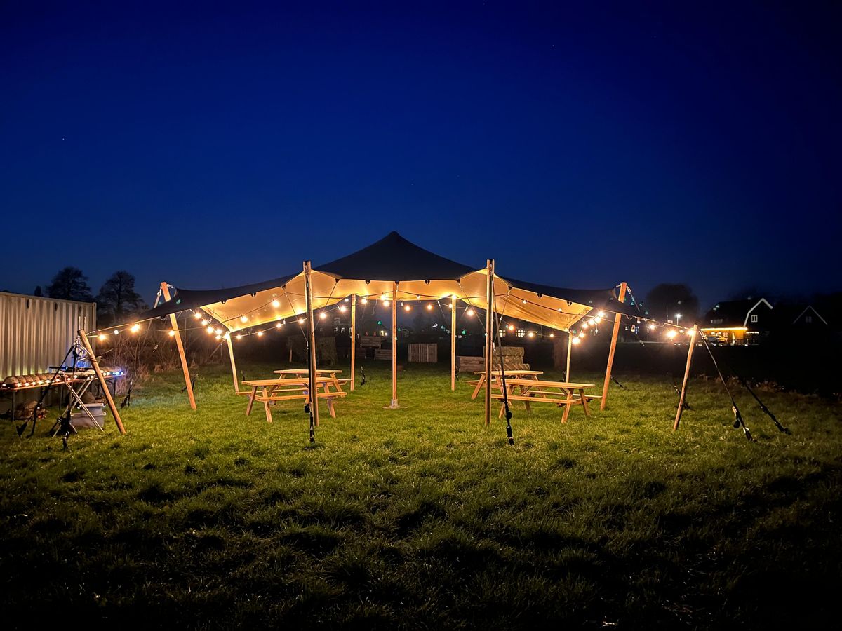 Verlichte feesttent in het veld bij avond