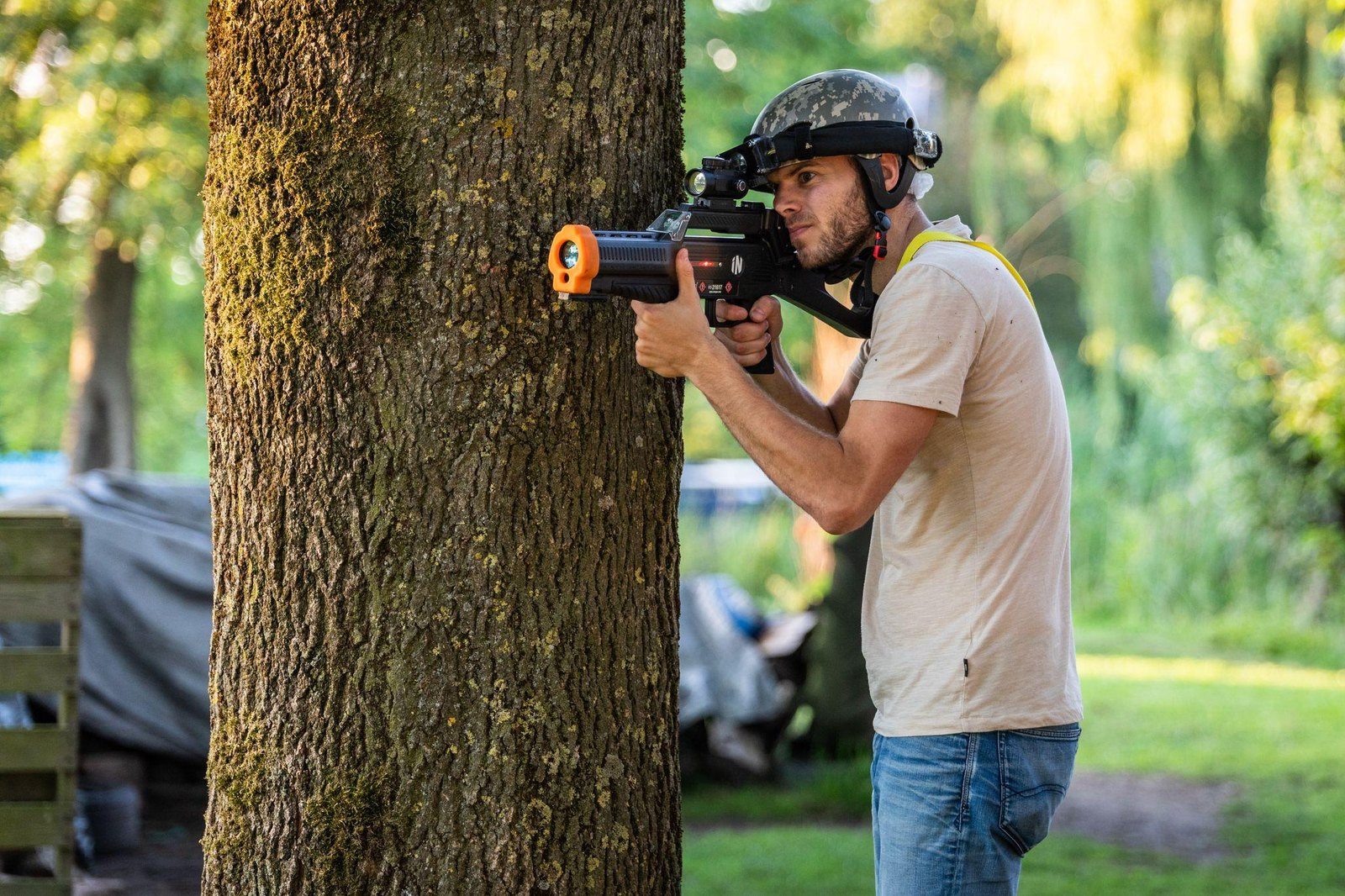 Volwassen speler in dekking achter een boom tijdens het outdoor lasergamen