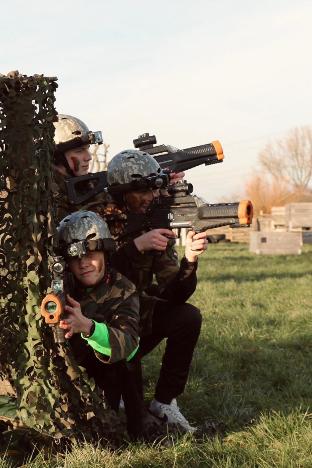 Spelers achter een camouflagenet tijdens het lasergamen