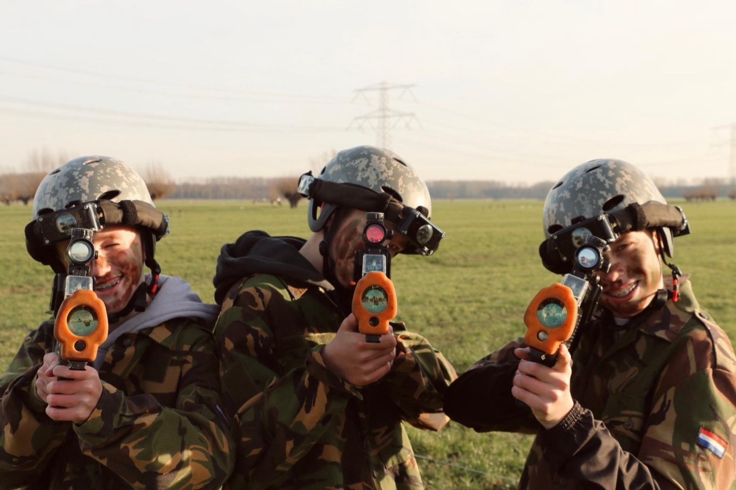 Drie lasergamers met hun geweer in het veld