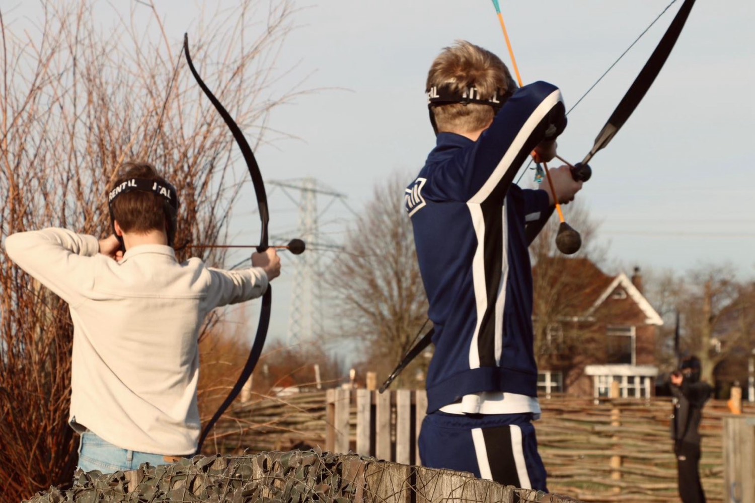 Twee spelers met pijl en boog bij een schutting