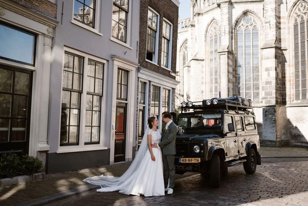 Bruidspaar bij de Land Rover Defender voor een kerk